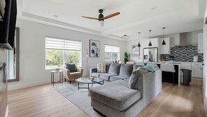 A spacious living room with a grey sectional sofa, a small coffee table, and a ceiling fan. - Urban Comfort King Bed Rooftop Backyard (Dallas)