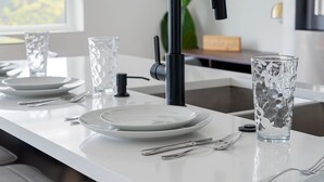 A modern kitchen with a white countertop, a black faucet, and a glass vase. - Urban Comfort King Bed Rooftop Backyard (Dallas)