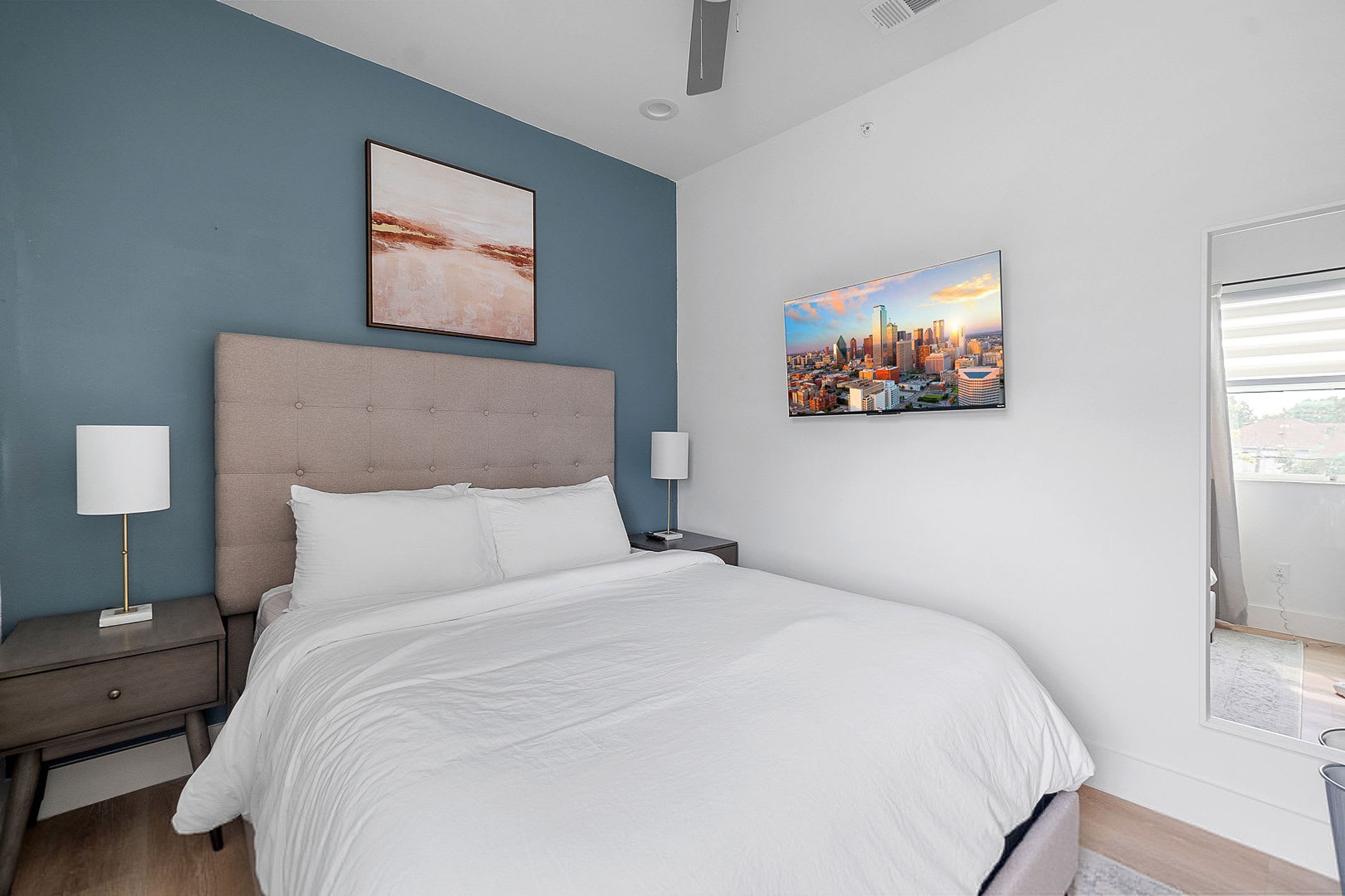 Un dormitorio moderno con una cama grande, dos mesitas de noche y dos lámparas de pared.