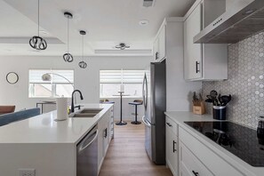 Una cocina moderna con armarios blancos, una isla central, un refrigerador y un salpicadero de azulejos hexagonales.