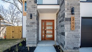 A modern house with a stone facade, a wooden front door, and a number '317' on the wall.