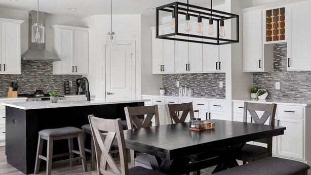A modern kitchen with white cabinets, a black island, and a dining area with wooden chairs and a dark table.