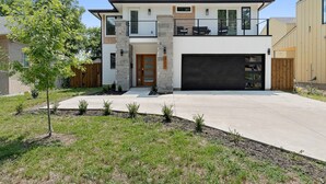 A modern two-story house with a garage, stone pillars, and a balcony.