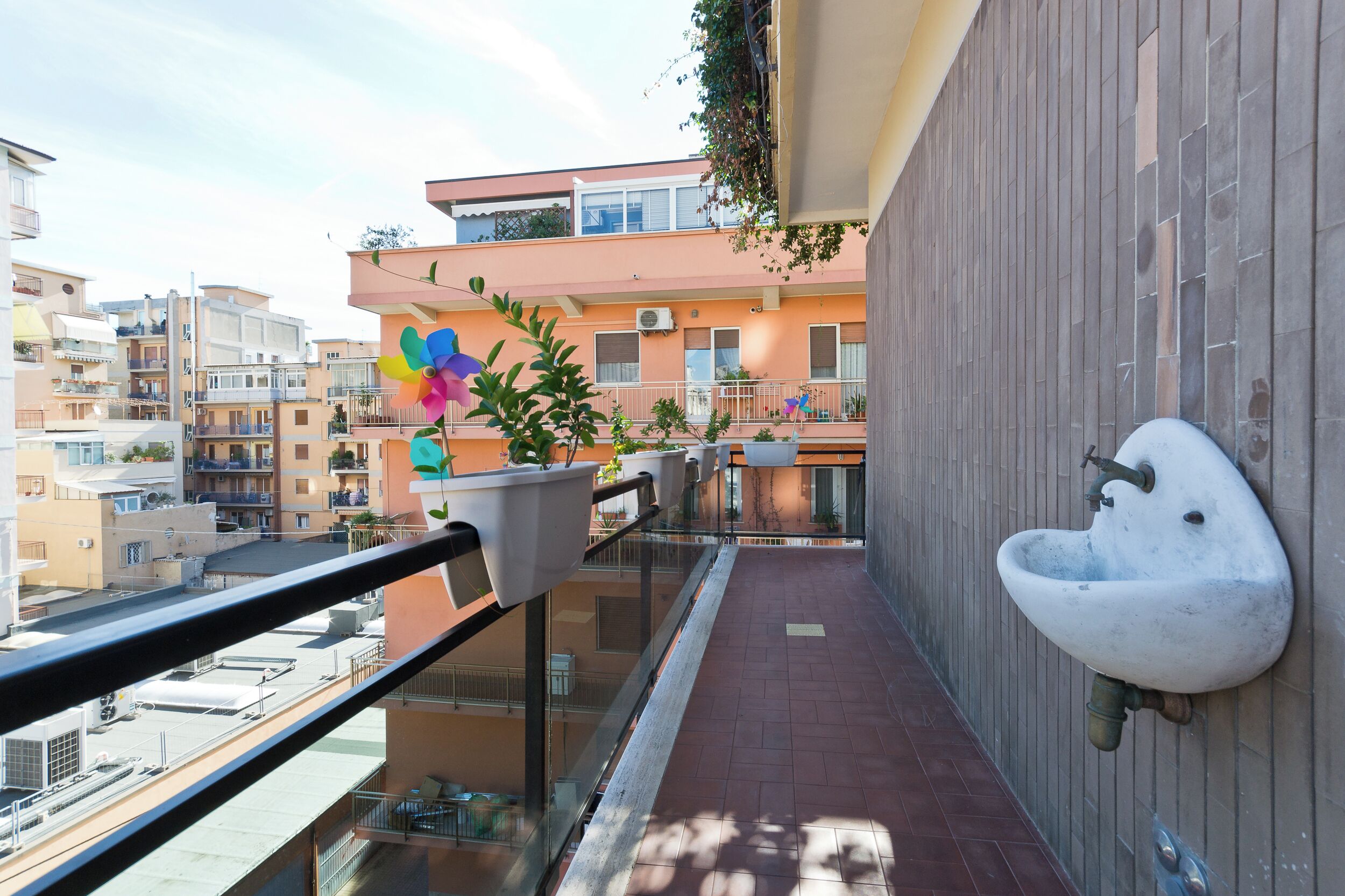 Ein Balkon mit Waschbecken, Blumentöpfen und einer farbenfrohen Blumendekoration.