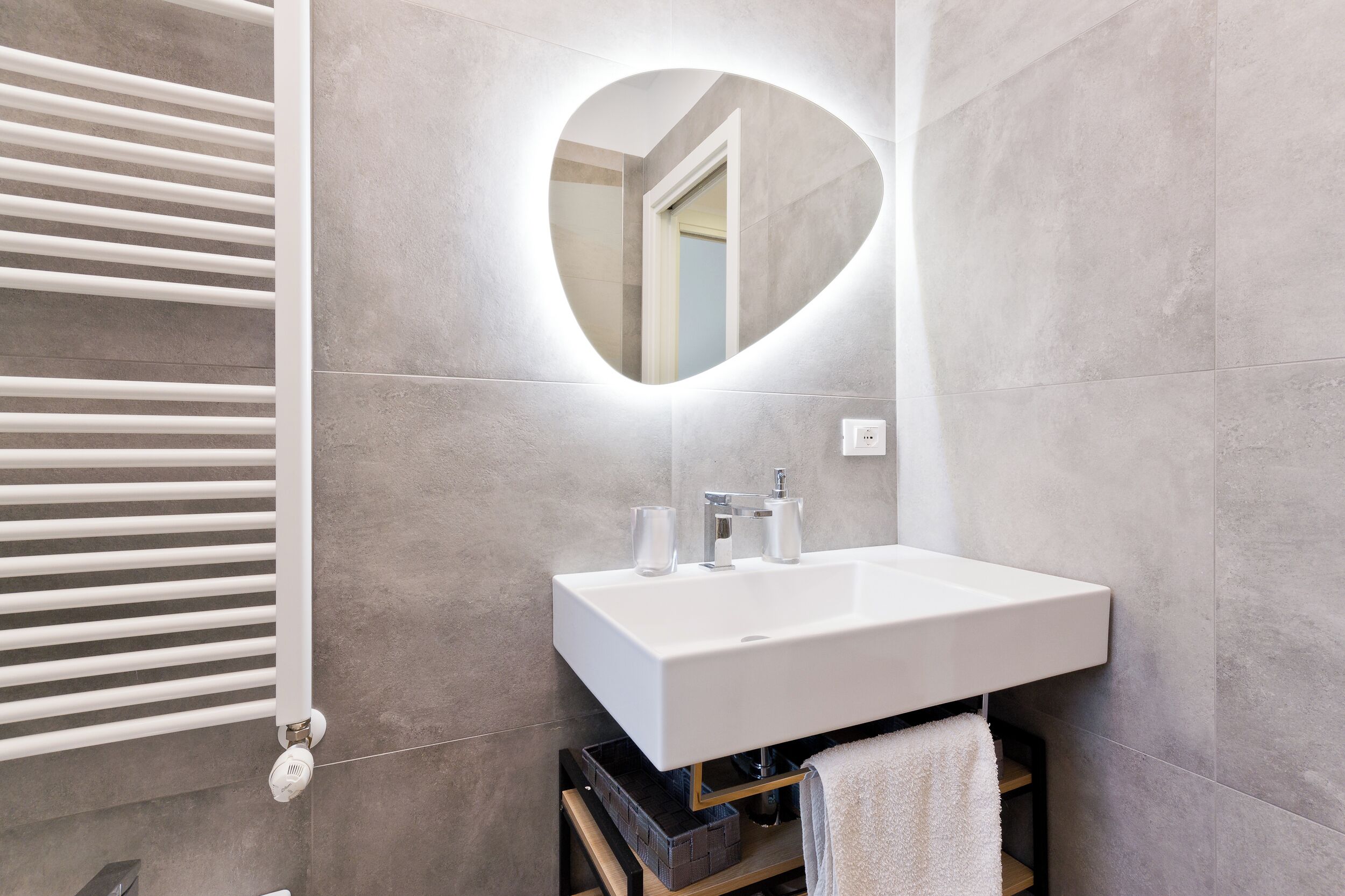 Une salle de bain avec un lavabo blanc, un miroir en forme de cœur et un porte-serviettes.