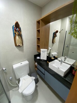 Une salle de bain moderne équipée de toilettes, d’un bidet, d’un lavabo et d’un miroir.