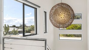 A modern interior with a large window, a unique woven light fixture, and a view of greenery outside. - Seaside Getaway - Point Lonsdale (Point Lonsdale)