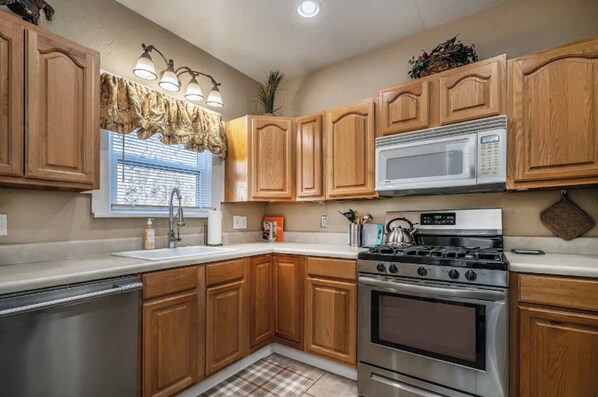 A kitchen with wooden cabinets, a stainless steel dishwasher, a microwave, and a stove.