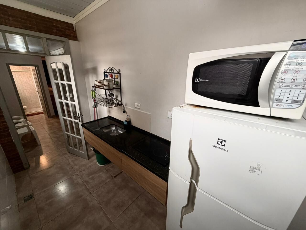 A compact kitchen with a white refrigerator, a microwave, and a sink.