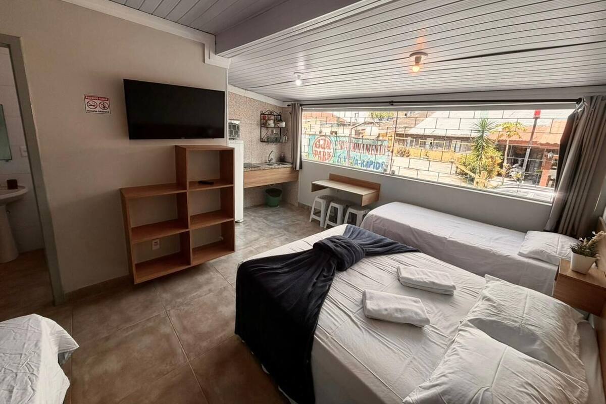 Une chambre d’hôtel équipée d’un lit, d’un bureau, d’une télévision et d’une fenêtre donnant sur des immeubles.