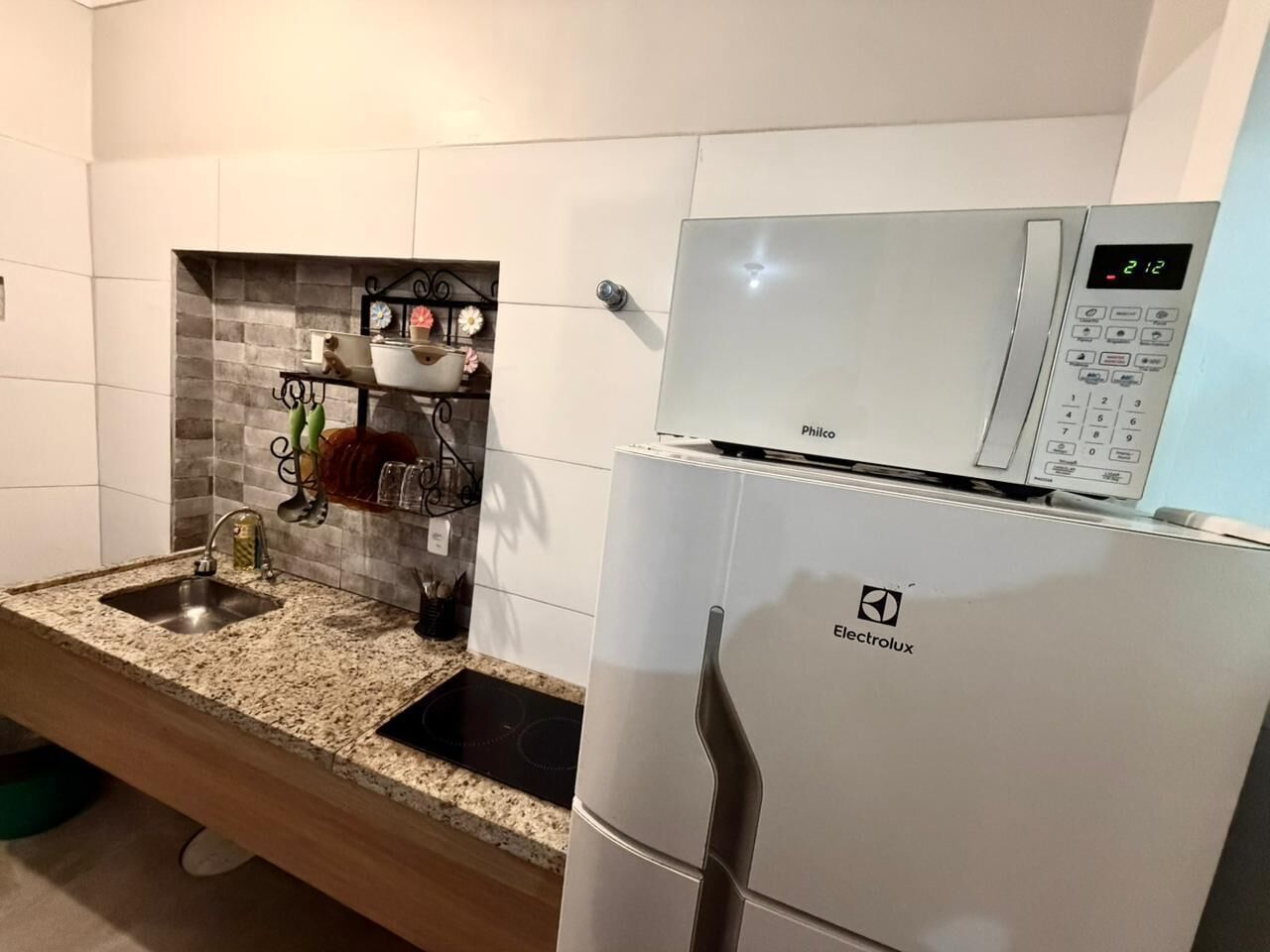 Eine kleine Küche mit einem weißen Kühlschrank, einer Spüle und einer Arbeitsfläche.
