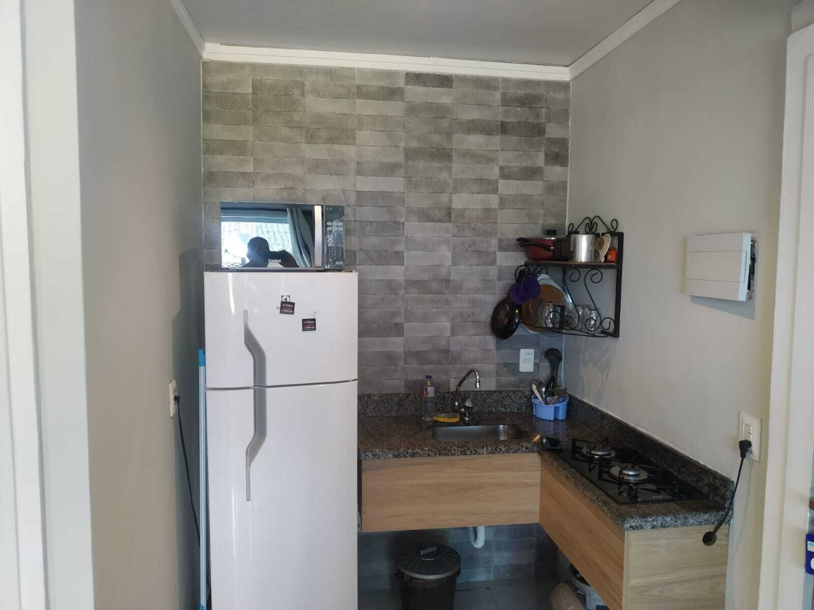 A compact kitchen with a white refrigerator, granite countertop, and a gas stove.