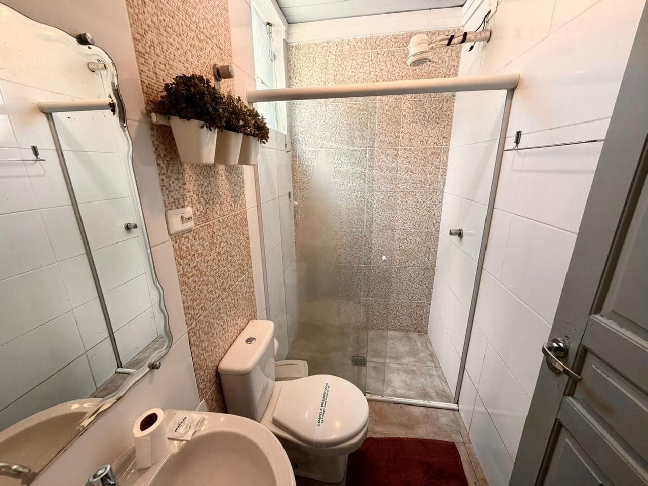 A compact bathroom with a shower, toilet, and sink.