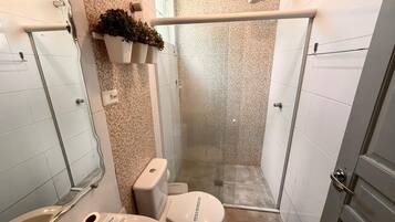 A compact bathroom with a shower, toilet, and sink.