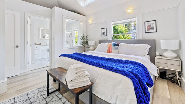 Un dormitorio con cama, mesita de noche y un banco con toallas.
