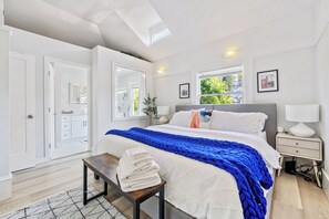Un dormitorio con cama, mesita de noche y un banco con toallas.