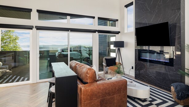 A modern living room with a leather sofa, a coffee table, and a flat-screen TV mounted on a marble wall.