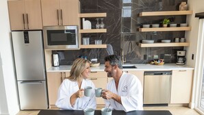 A modern kitchen with a refrigerator, microwave, and coffee maker. There is a dining table with two people seated.
