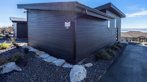 Een modern huis met een donkere gevel, een oprit en een heldere lucht.