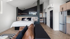 A modern hotel room with a large bed, a bench, a dining area, and a kitchenette. - Branson's Perfect Luxury Romantic Getaway (Branson)