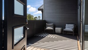 A modern outdoor seating area with two chairs and a small table, a wooden deck, and a view of the sky and trees. - Branson's Perfect Luxury Romantic Getaway (Branson)