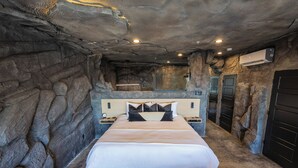 A bedroom with a large bed, a headboard, bedside tables, and a wall-mounted air conditioning unit.