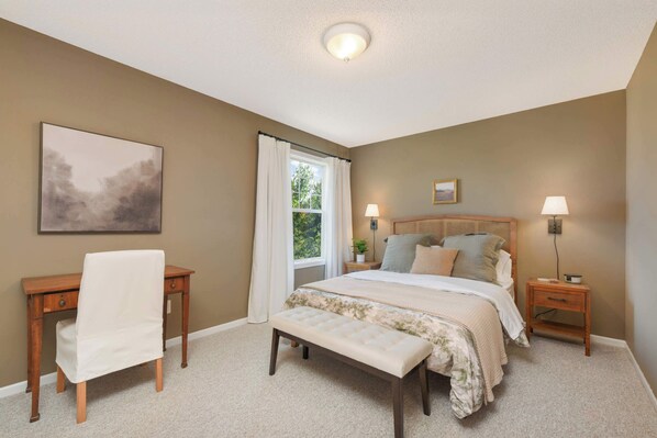 A bedroom with a bed, bedside tables, a chair, and a window.