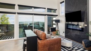 Ein modernes Wohnzimmer mit einer Ledersofa, einem Couchtisch und einem Flachbildfernseher, der an einer Marmorwand angebracht ist.