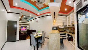 A modern kitchen with white cabinets, a built-in oven, and a microwave. - Rb's Three Storey House (Zamboanga)