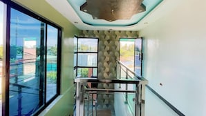A modern interior with a glass staircase, large windows, and a unique ceiling design. - Rb's Three Storey House (Zamboanga)