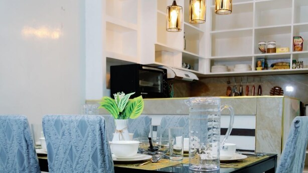 A dining area with a table set for four, featuring patterned chairs, a vase with green leaves, and a pitcher. - Rb's Three Storey House (Zamboanga)