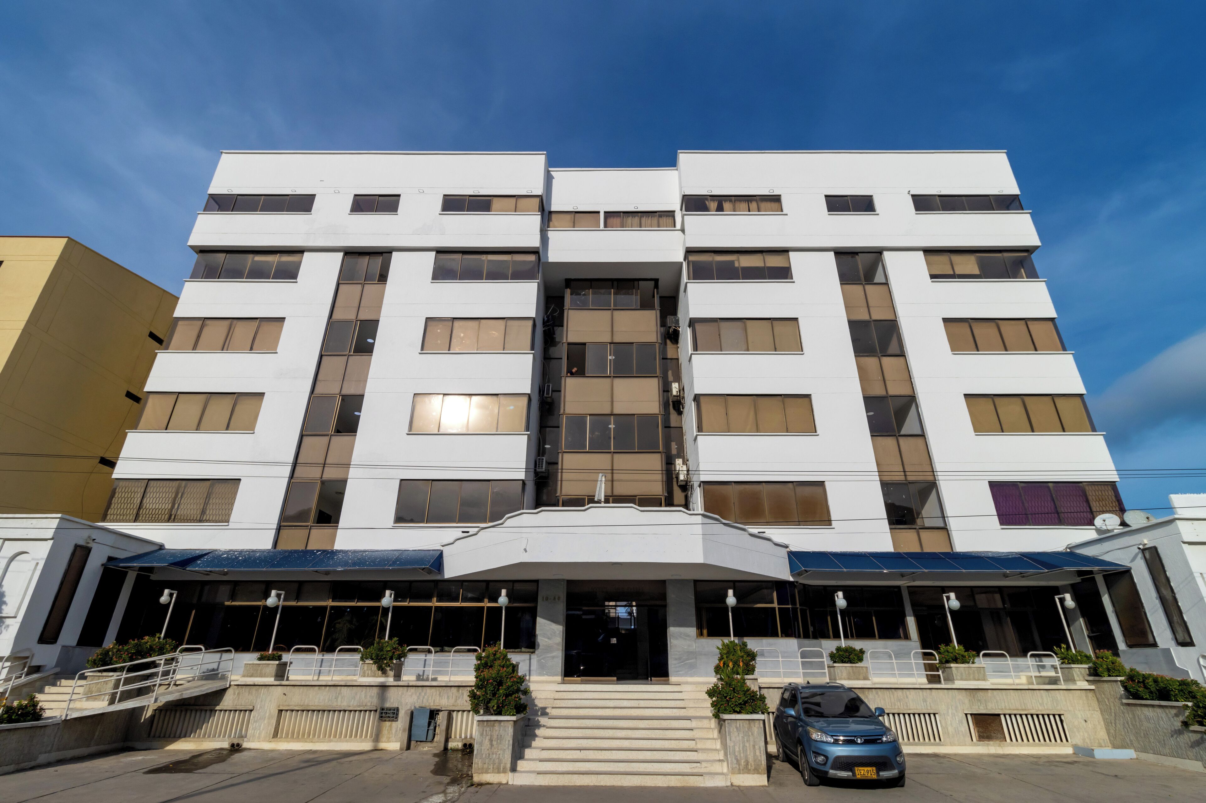 A modern multi-story hotel with a symmetrical facade, large windows, and a central entrance with steps.