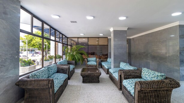 A modern lobby with wicker furniture, large windows, and a tiled floor. - Hotel Axis Inn By GEH Suites (Santa Marta)
