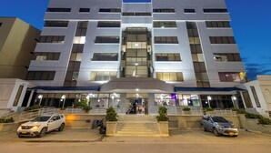 A modern hotel with a symmetrical facade, multiple balconies, and a central entrance with steps. - Hotel Axis Inn By GEH Suites (Santa Marta)