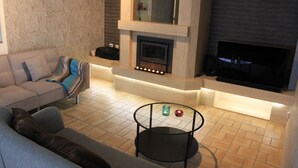 A modern living room with a sofa, a fireplace, and a flat-screen TV. - Maison Spacieuse near Brussels (Meise)
