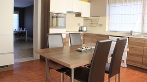 A modern kitchen with a dining area, featuring a wooden table, chairs, and built-in appliances. - Maison Spacieuse near Brussels (Meise)
