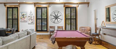 A room with a pool table, a sofa, and a wooden ceiling.