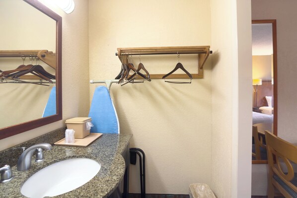Een badkamer met een granieten wastafel, een spiegel, een handdoekrek en een handdoekdispenser.