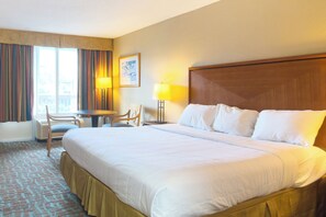 Een hotelkamer met een groot bed, een bureau, een stoel en een raam met gordijnen.