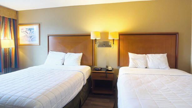Ein Hotelzimmer mit zwei Betten, einem Nachttisch und einer Lampe.