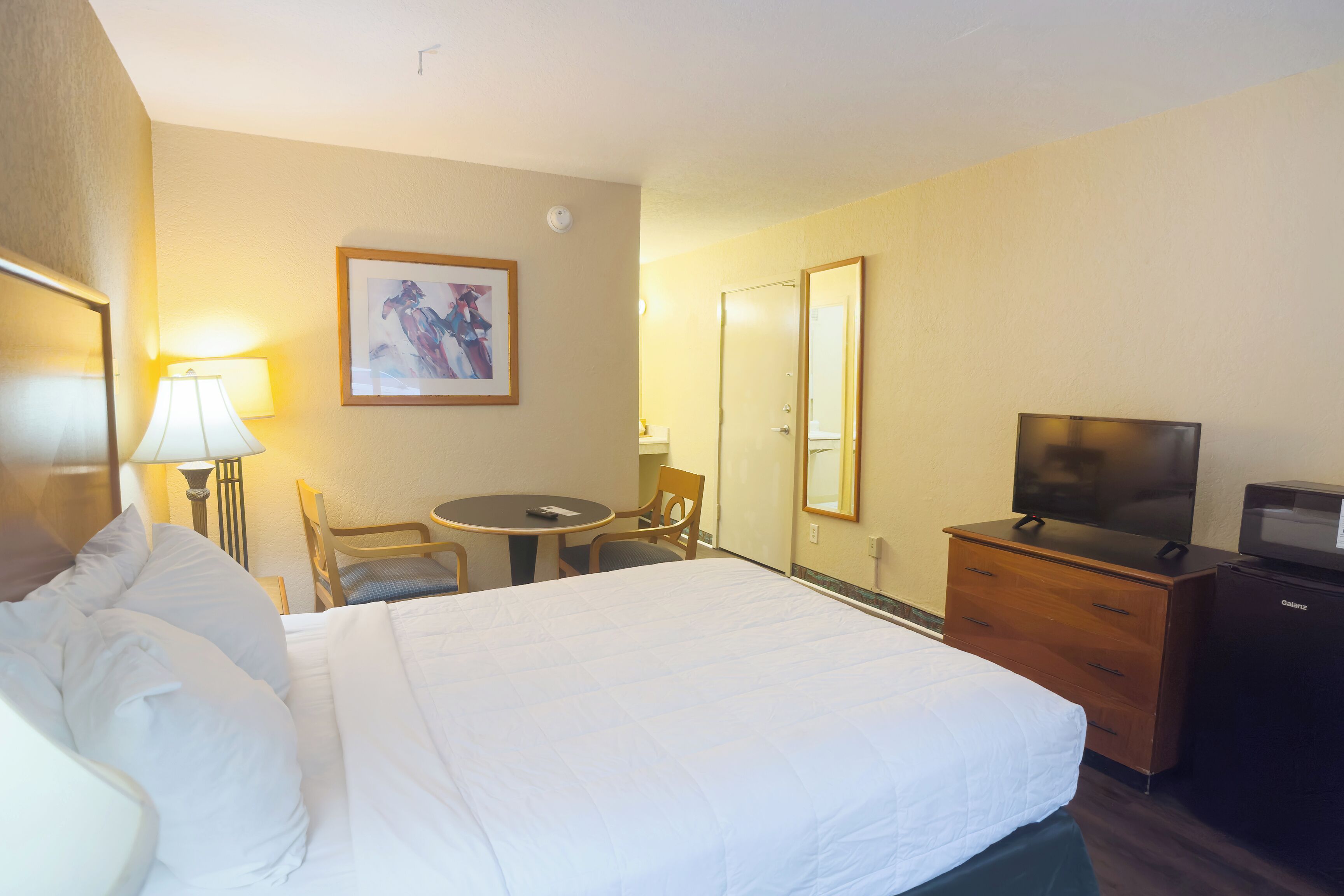 Ein Hotelzimmer mit einem Bett, einem Schreibtisch mit Stuhl, einem Fernseher und einem Schminktisch.