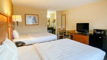 A hotel room with two beds, a desk with a television, a chair, and a dresser.