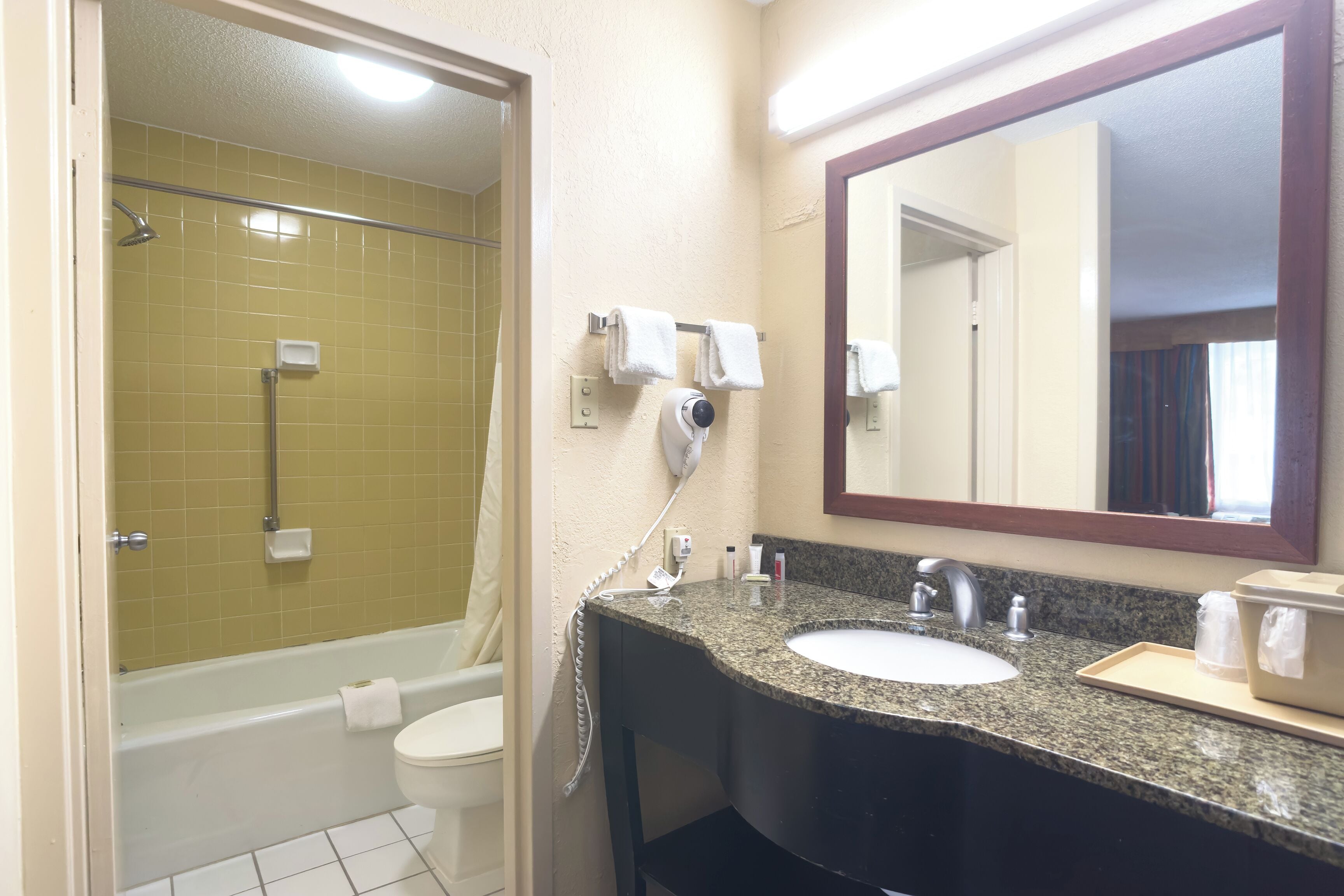 A bathroom with a bathtub, toilet, sink, and a large mirror.