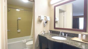 A bathroom with a bathtub, toilet, sink, and a large mirror.
