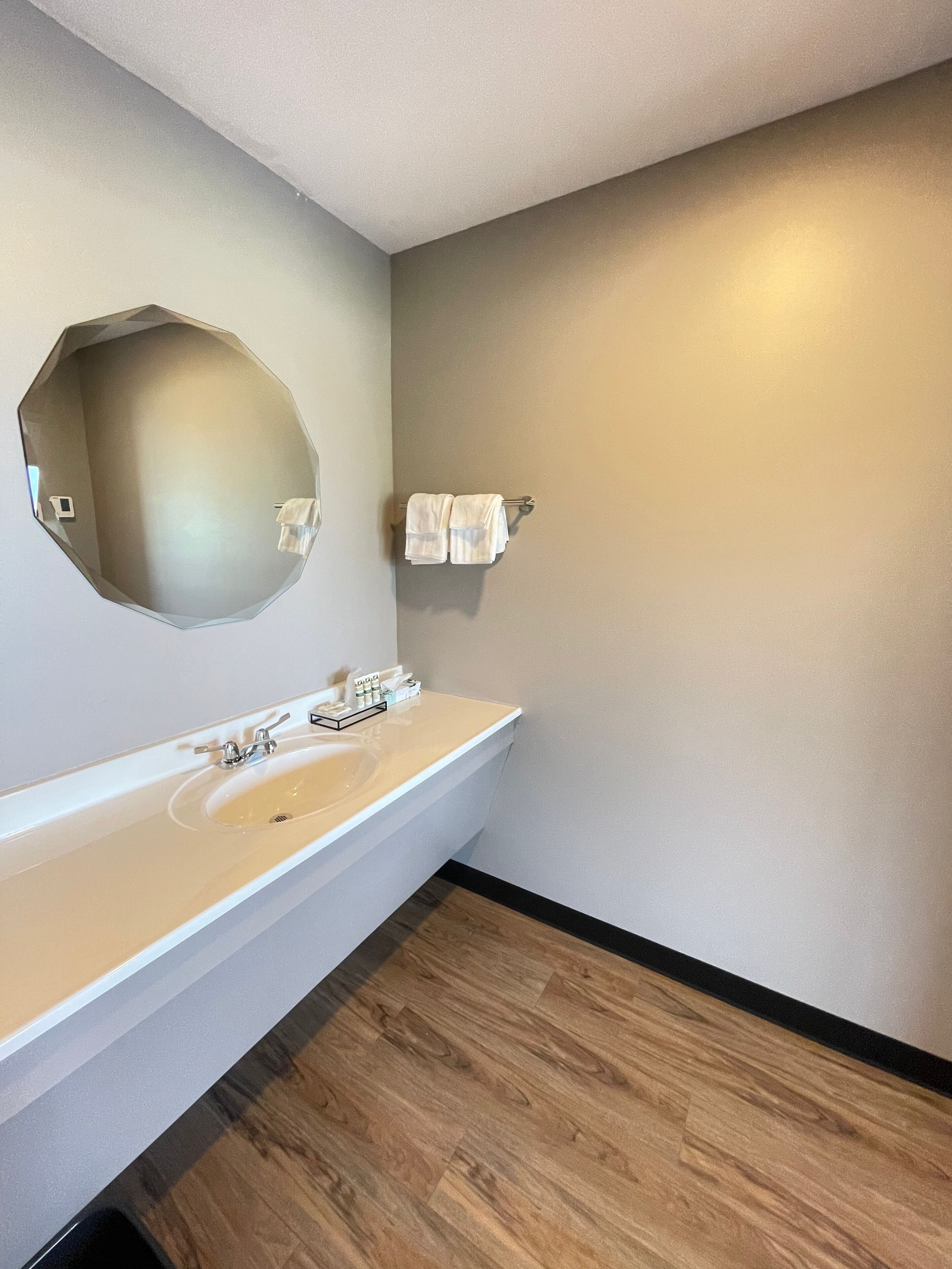 A bathroom with a large oval mirror, a white sink, and a towel rack.