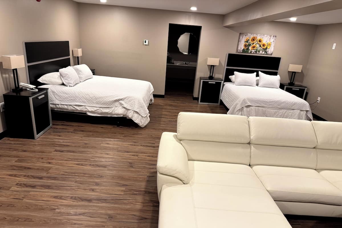 A hotel room with two beds, a sofa, and a mirror.