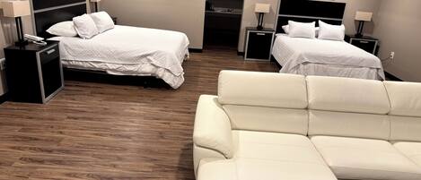 A hotel room with two beds, a sofa, and a mirror.