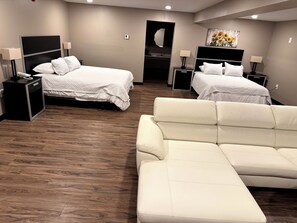 A hotel room with two beds, a sofa, and a mirror.