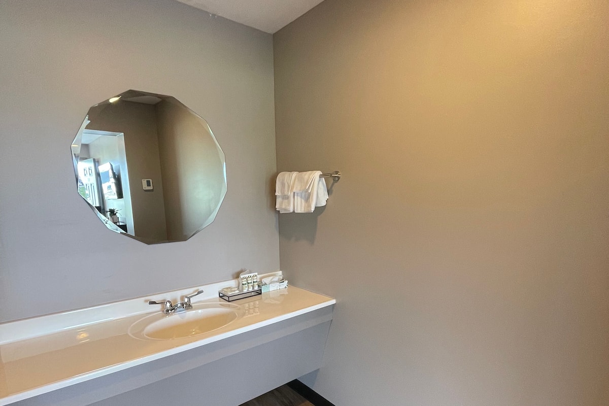 A bathroom with a white sink, a round mirror, and a towel rack.