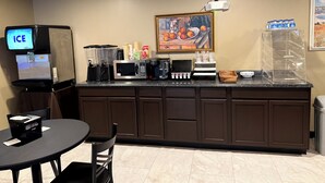 A kitchenette with a coffee machine, microwave, and a water dispenser. There is a painting on the wall and a trash can in the corner. - Four Seasons Inn (Gallipolis)